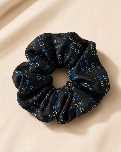 Second Soie handmade scrunchie made from a black Celine scarf with blue and ivory logo lettering on a neutral surface