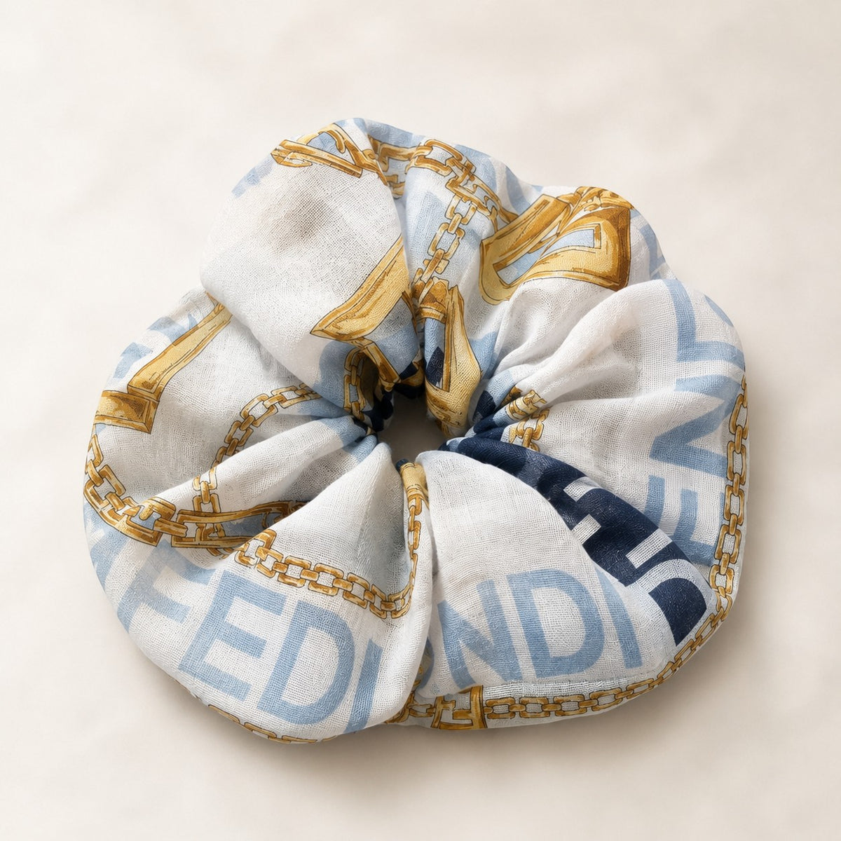 Second Soie jumbo scrunchie made from an authentic Fendi scarf in ice blue, white, and gold chain print.