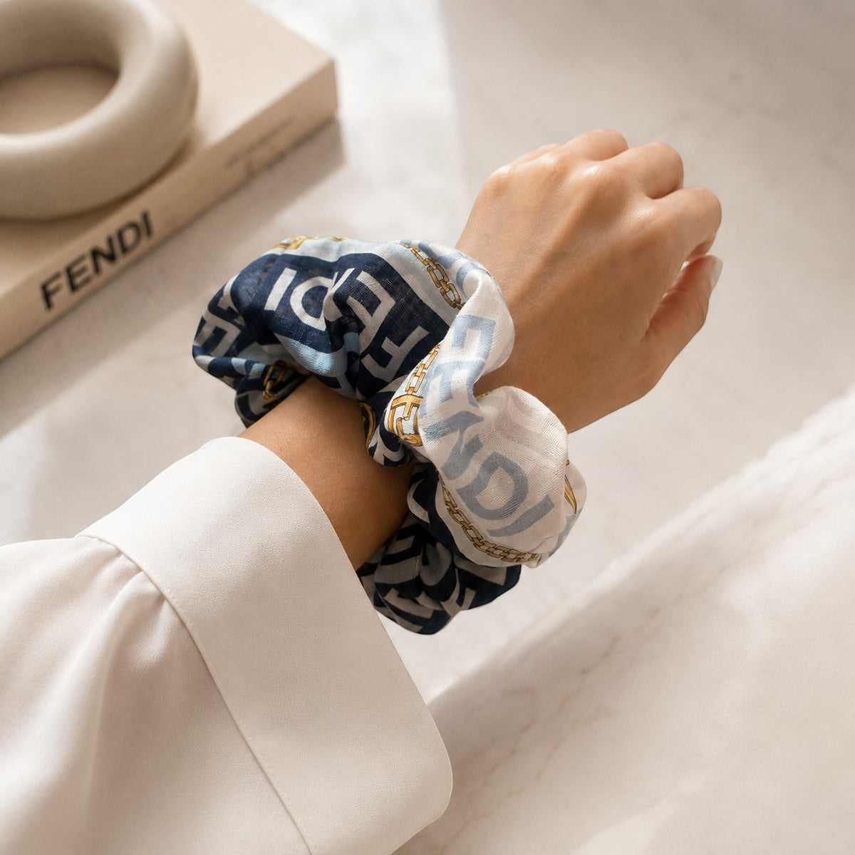 Second Soie jumbo Fendi scarf scrunchie in navy and ice blue worn on a wrist, featuring gold chain-inspired patterns.