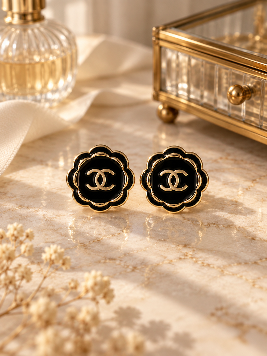 Second Soie vintage Chanel button earrings featuring black enamel floral petals and gold-tone CC logos on marble.