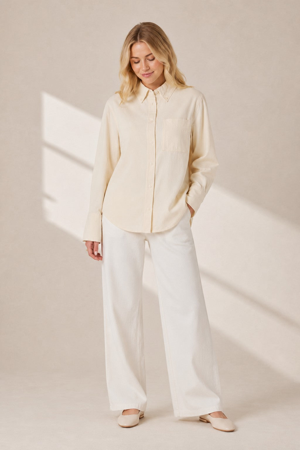Model wearing a Second Soie ivory cotton denim overshirt with a pointed collar and chest pocket, paired with white pants