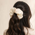 Second Soie jumbo scrunchie in ivory silk with blush floral print worn in a half-up hairstyle on dark wavy hair