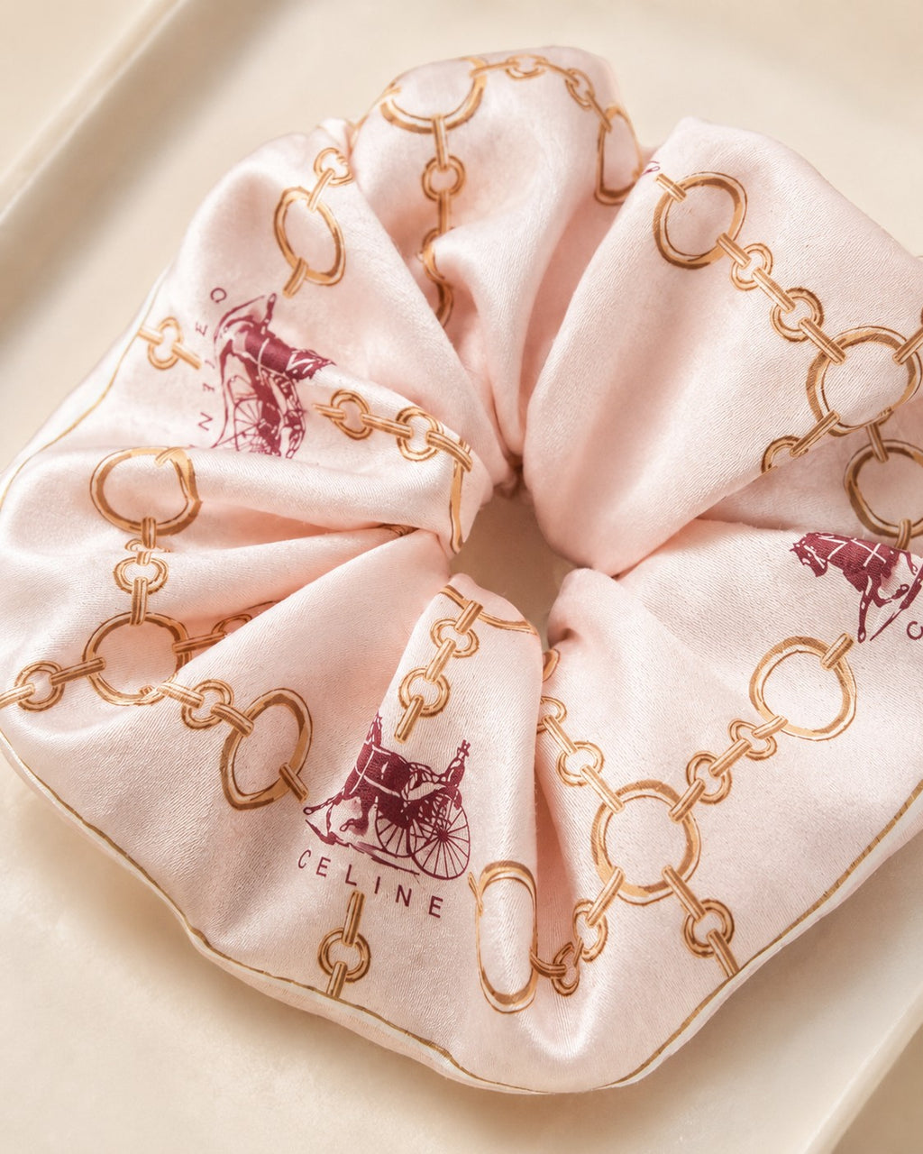 Second Soie jumbo silk scrunchie in blush with a Celine equestrian print featuring gold chains and burgundy carriages.