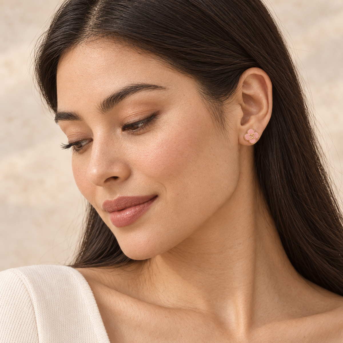 Model wearing Second Soie vintage Chanel blush-pink enamel clover stud earrings with gold CC logo on pierced ears