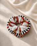 Second Soie jumbo scrunchie made from a vintage Fendi cotton scarf with red ribbon, black stripes, and gold motifs.