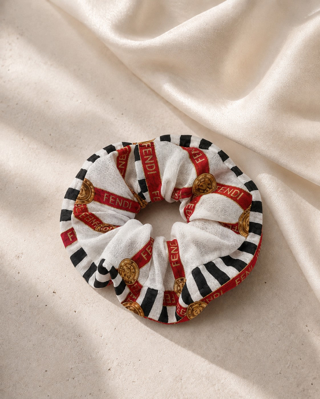 Second Soie jumbo scrunchie made from a vintage Fendi cotton scarf with red ribbon, black stripes, and gold motifs.