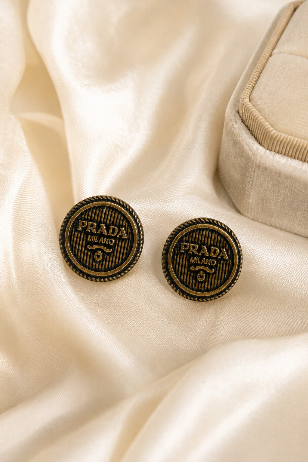 Second Soie handcrafted vintage Prada button earrings in antiqued gold-tone with rope border on cream silk fabric.