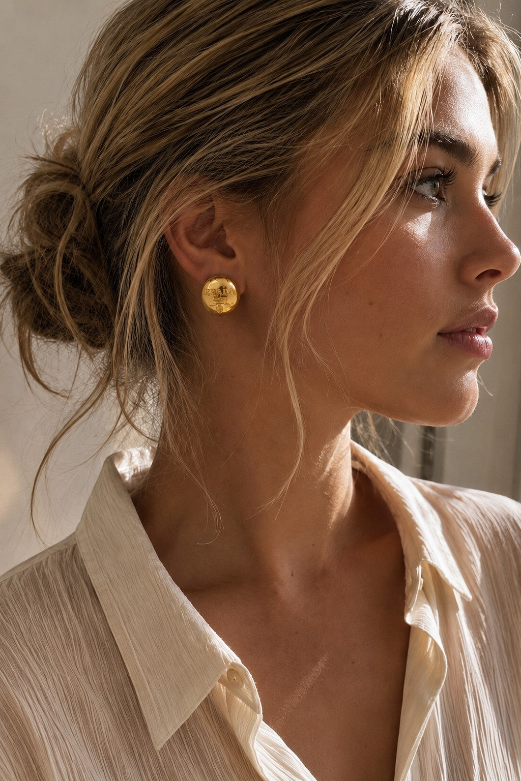 Second Soie vintage Prada Milano gold button earrings worn by a woman with a soft, polished finish.