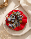 Second Soie vintage Roberta di Camerino scarf scrunchie in red with navy, white, and gold chain print on a tray.